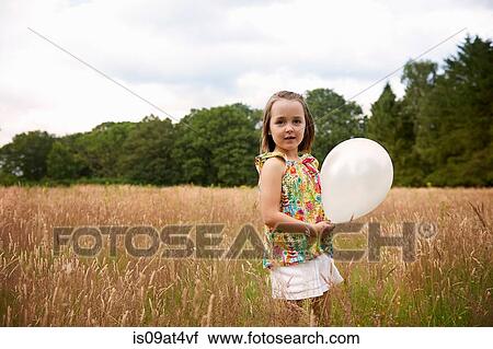 Girl in tall grass holding balloon looking at camera View Large Photo Image Stock Image - Girl in tall grass holding balloon looking at camera. Fotosearch