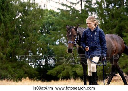 Girl leading horse in field View Large Photo Image Picture - Girl leading horse in field. Fotosearch