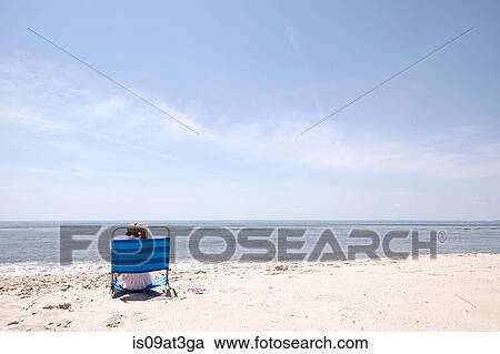 Girl looking over her shoulder from deck chair on beach View Large Photo Image Stock Image - Girl looking over her shoulder from deck chair on beach. Fotosearch