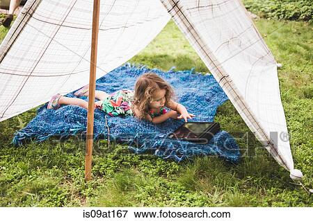Girl lying in homemade garden tent using touchscreen on digital tablet View Large Photo Image Stock Photo - Girl lying in homemade garden tent using touchscreen on digital tablet. Fotosearch
