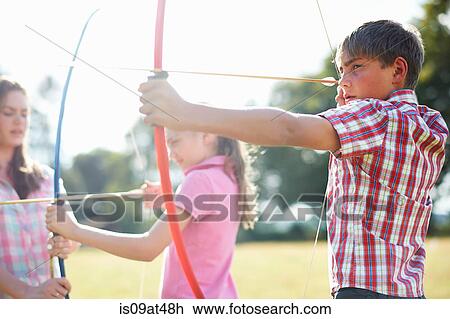 Girl practicing archery with teenage sister and brother View Large Photo Image Stock Image - Girl practicing archery with teenage sister and brother. Fotosearch