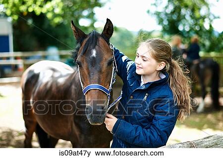 Stock Photo - Girl putting halter onto horse. Fotosearch