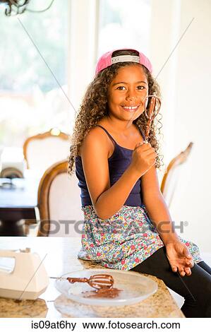 Girl sitting on kitchen counter holding whisk covered in cake mix looking at camera smiling View Large Photo Image Stock Photo - Girl sitting on kitchen counter holding whisk covered in cake mix looking at camera smiling. Fotosearch