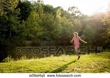 Girl skipping along river bank arms open View Large Photo Image Stock Photography - Girl skipping along river bank arms open. Fotosearch