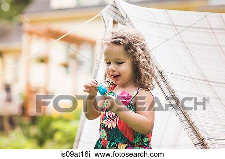 Girl touching ice lolly in garden View Large Photo Image Stock Image - Girl touching ice lolly in garden. Fotosearch