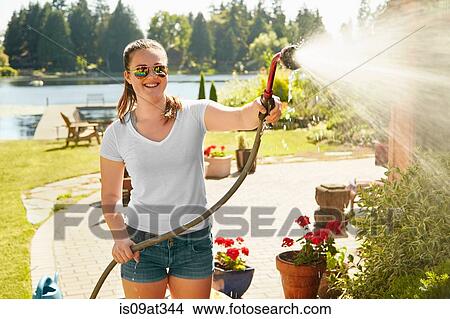 "Girl watering plants at lake house, Seattle, Washington, USA" View Large Photo Image Picture - "Girl watering plants at lake house, Seattle, Washington, USA". Fotosearch