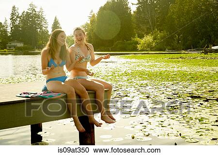 Stock Image - "Girls in bikini enjoying lake, Seattle, Washington, USA". Fotosearch