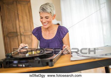 Happy mature woman playing vinyl on record player View Large Photo Image Stock Photo - Happy mature woman playing vinyl on record player. Fotosearch