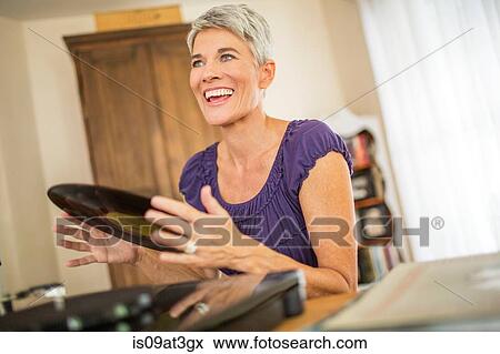 Happy mature woman playing vinyl records View Large Photo Image Stock Photo - Happy mature woman playing vinyl records. Fotosearch
