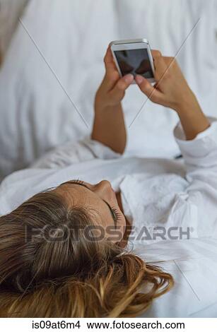 High angle over shoulder view of young woman using smartphone View Large Photo Image Picture - High angle over shoulder view of young woman using smartphone. Fotosearch