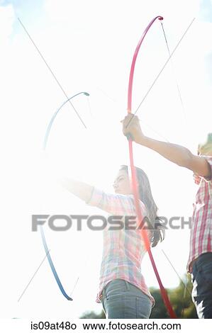 Low angle view of teenage brother and sister practicing archery View Large Photo Image Picture - Low angle view of teenage brother and sister practicing archery. Fotosearch