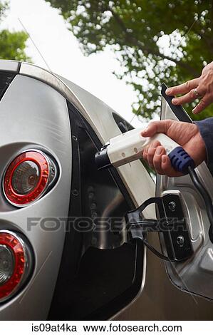 Stock Image - Man charging electric car. Fotosearch