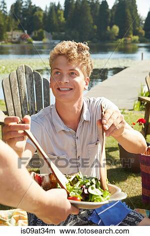 "Man helping himself to salad at lake party, Seattle, Washington, USA" View Large Photo Image Picture - "Man helping himself to salad at lake party, Seattle, Washington, USA". Fotosearch