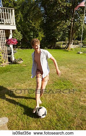 Stock Image - Man playing football in garden. Fotosearch