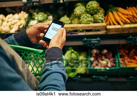 Man shopping and using smartphone in supermarket View Large Photo Image Stock Image - Man shopping and using smartphone in supermarket. Fotosearch