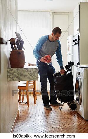Man unpacking groceries at home View Large Photo Image Stock Image - Man unpacking groceries at home. Fotosearch