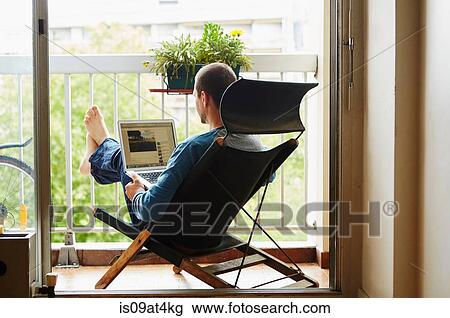 Man using laptop on balcony View Large Photo Image Stock Image - Man using laptop on balcony. Fotosearch