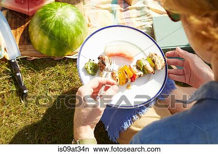 Man with plate of kebab at picnic party View Large Photo Image Picture - Man with plate of kebab at picnic party. Fotosearch