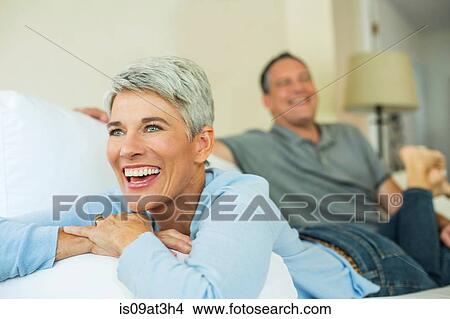 Mature couple laughing and relaxing on sofa View Large Photo Image Picture - Mature couple laughing and relaxing on sofa. Fotosearch