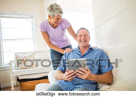 Mature couple laughing whilst using digital tablet View Large Photo Image Stock Photo - Mature couple laughing whilst using digital tablet. Fotosearch