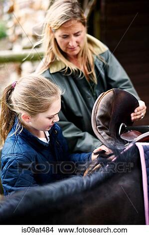 Mature woman and daughter saddling horse View Large Photo Image Picture - Mature woman and daughter saddling horse. Fotosearch