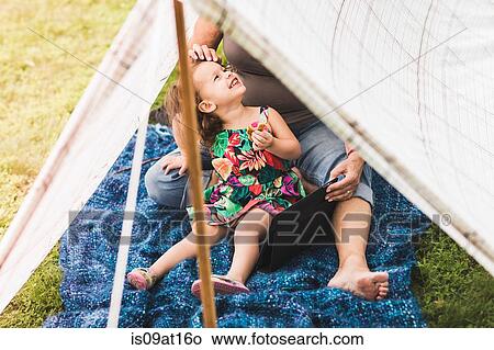 Mature woman and granddaughter sitting in homemade garden tent using digital tablet View Large Photo Image Picture - Mature woman and granddaughter sitting in homemade garden tent using digital tablet. Fotosearch