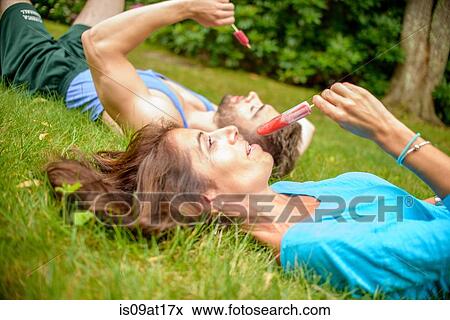 "Mature woman and young man lying on grass, eating ice lollies" View Large Photo Image Stock Photo - "Mature woman and young man lying on grass, eating ice lollies". Fotosearch
