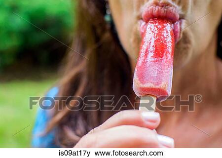 Stock Photo - "Mature woman eating ice lollies, close-up". Fotosearch