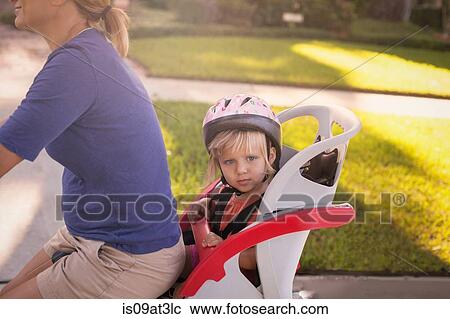 Stock Image - Mature woman on bicycle with daughter sitting in child's seat behind her. Fotosearch