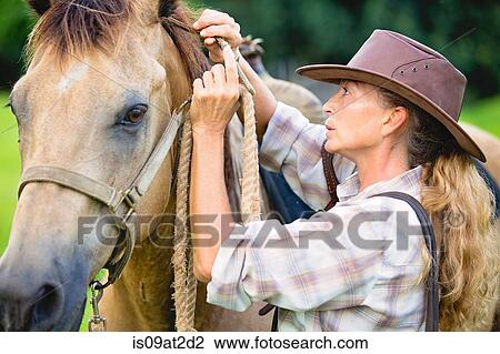 Mature woman securing horses reigns View Large Photo Image Stock Image - Mature woman securing horses reigns. Fotosearch