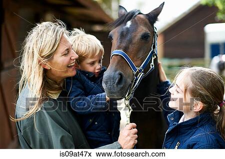 Stock Photo - Mature woman with son and daughter petting horse. Fotosearch