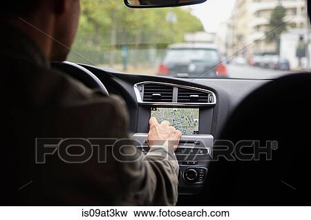 Stock Photo - "Mid adult man sitting in car, using gps". Fotosearch