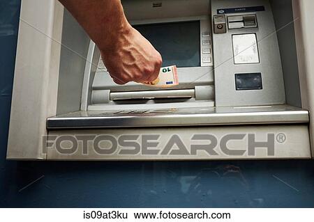 Stock Photograph - "Mid adult man using cash machine, focus on hands". Fotosearch