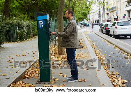 Mid adult man using parking meter in street View Large Photo Image Stock Photo - Mid adult man using parking meter in street. Fotosearch