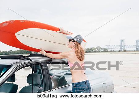"Mid adult woman at beach, removing surfboard from car roof" View Large Photo Image Stock Photography - "Mid adult woman at beach, removing surfboard from car roof". Fotosearch