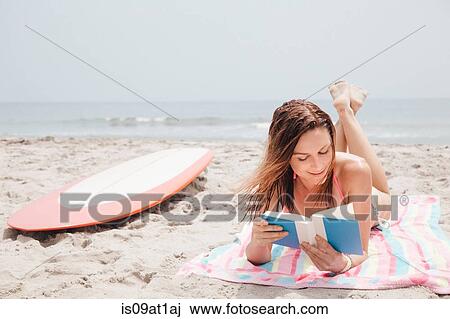 "Mid adult woman lying on beach, reading book" View Large Photo Image Stock Image - "Mid adult woman lying on beach, reading book". Fotosearch