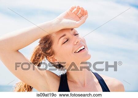 "Mid adult woman on beach, arm resting on head" View Large Photo Image Picture - "Mid adult woman on beach, arm resting on head". Fotosearch