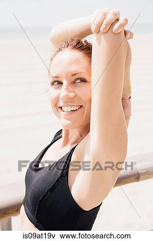 Stock Photo - "Mid adult woman on beach, stretching arms". Fotosearch