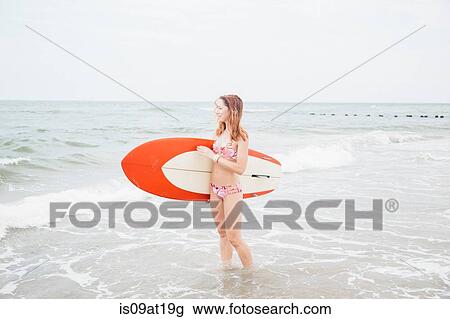 "Mid adult woman standing in sea, holding surfboard" View Large Photo Image Stock Image - "Mid adult woman standing in sea, holding surfboard". Fotosearch