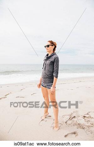 "Mid adult woman standing on beach, looking at view" View Large Photo Image Stock Image - "Mid adult woman standing on beach, looking at view". Fotosearch