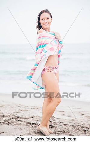 "Mid adult woman standing on beach, towel wrapped around her" View Large Photo Image Stock Image - "Mid adult woman standing on beach, towel wrapped around her". Fotosearch