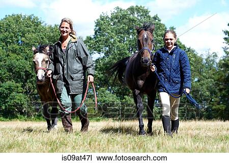 Mother and daughter leading horses in field View Large Photo Image Stock Image - Mother and daughter leading horses in field. Fotosearch