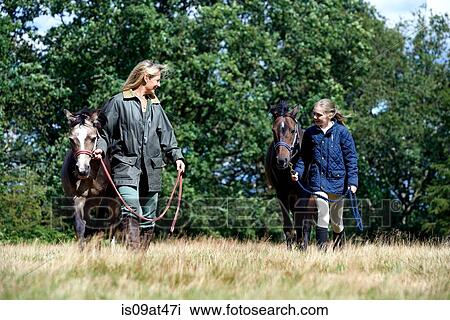 Mother and daughter walking horses in field View Large Photo Image Stock Image - Mother and daughter walking horses in field. Fotosearch