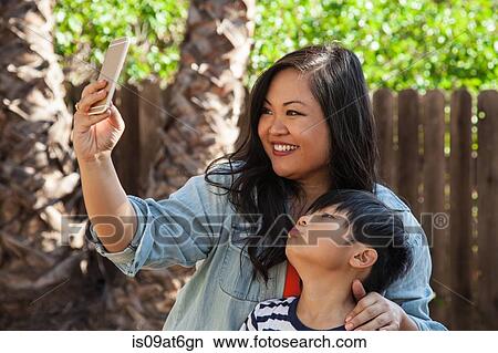 Mother and son posing for smartphone selfie in garden View Large Photo Image Picture - Mother and son posing for smartphone selfie in garden. Fotosearch