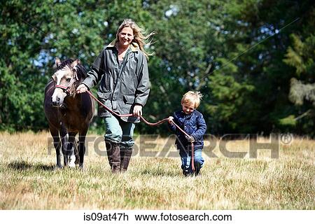Mother and son walking pony in field View Large Photo Image Stock Image - Mother and son walking pony in field. Fotosearch