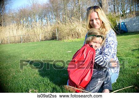 Stock Photograph - Mother hugging son in red superhero cape. Fotosearch