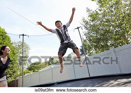 Mother watches son jumping on trampoline in garden View Large Photo Image Picture - Mother watches son jumping on trampoline in garden. Fotosearch