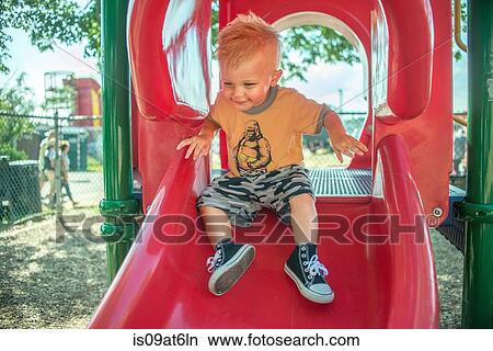 One baby boy playing on red playground slide View Large Photo Image Picture - One baby boy playing on red playground slide. Fotosearch