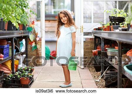 Portrait of girl holding watering can in greenhouse View Large Photo Image Stock Photograph - Portrait of girl holding watering can in greenhouse. Fotosearch