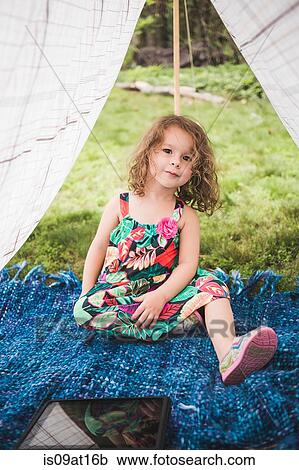 Stock Image - Portrait of girl in homemade garden tent with digital tablet. Fotosearch